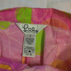 K&ouml;nnte beinhalten: Ein rosa-gr&uuml;ner Lilly Pulitzer Rock mit Paisley-Muster. Das Etikett lautet "Lilly Pulitzer" und enth&auml;lt die Stoffzusammensetzung: 97 % Baumwolle und 3 % Elasthan. Das Etikett lautet auch "Hergestellt in China" und "M&ouml;gliche Einlaufgefahr von 5 %."