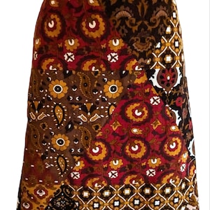 May include: A brown, red and gold patchwork skirt with a paisley and floral print. The skirt is made of corduroy and has a straight silhouette.