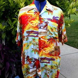 May include: A short-sleeved button-down shirt with a vibrant tropical print. The shirt features a colorful design of palm trees, sunsets, and ocean scenes in shades of red, yellow, blue, and purple. The shirt is displayed on a black mannequin.