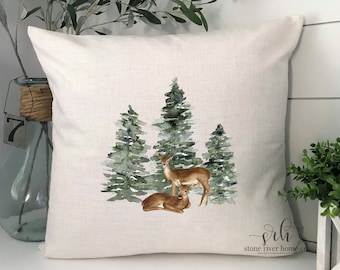 May include: A white throw pillow featuring a watercolour design of two deer in a forest of green trees. The pillow has the text "srh stone river home co" in the bottom right corner.