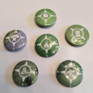 May include: Six green and white compass-style buttons with different Disney park icons. The icons include a tree, a castle, a spaceship, a teacup, a castle, and a building.