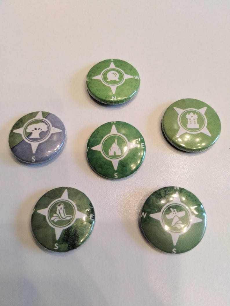 May include: Six green and white compass-style buttons with different Disney park icons. The icons include a tree, a castle, a spaceship, a teacup, a castle, and a building.