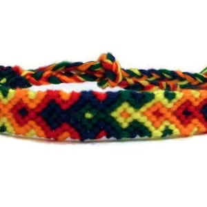 Może przedstawiać: Ręcznie robiona bransoletka przyjaźni z tkanym wzorem w kolorach czerwonym, żółtym, pomarańczowym, zielonym i granatowym. Bransoletka jest regulowana za pomocą plecionego zapięcia. Kolorowy dodatek.