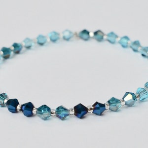 Peut inclure: Un bracelet délicat composé de perles de cristal bleues et turquoise. Les perles sont facettées et présentent un effet dégradé, passant d'un bleu foncé à un turquoise plus clair.
