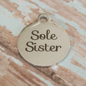 May include: A silver round charm with the words "Sole Sister" engraved on it.