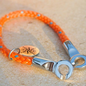 May include: Orange rope bracelet with a compass charm and silver metal clasp.