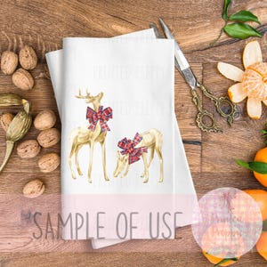 Puede incluir: Toalla decorativa blanca con dos ciervos dorados con lazos de cuadros rojos y negros. La toalla tiene el texto "SAMPLE OF USE" impreso. La toalla est&aacute; sobre una superficie de madera con nueces y tijeras.