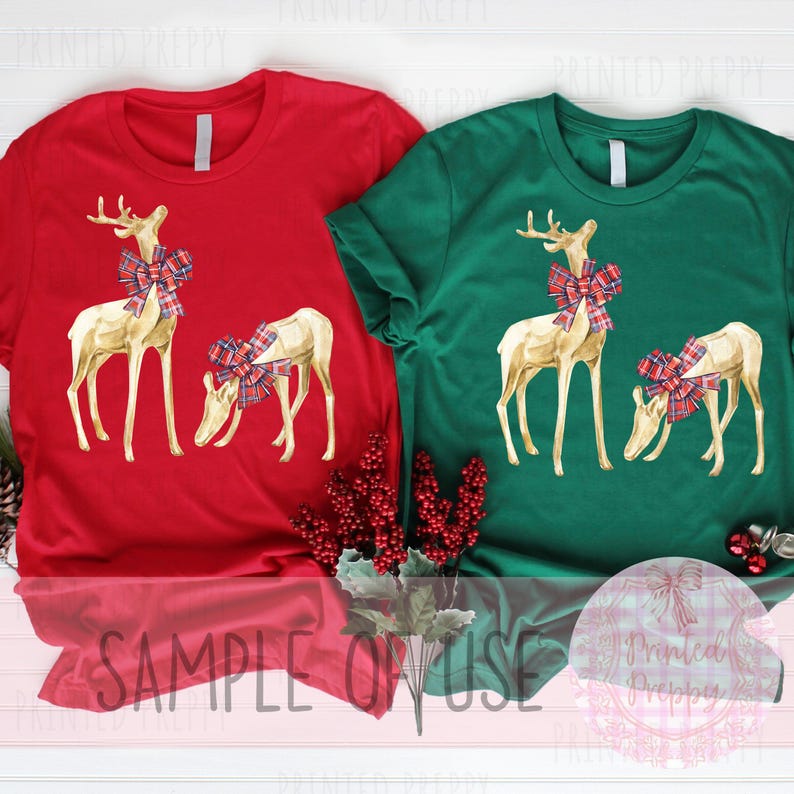 Puede incluir: Dos camisetas de manga corta, una roja y otra verde, cada una con una ilustraci&oacute;n en acuarela de dos renos. Los renos tienen cuerpos dorados y est&aacute;n adornados con lazos a cuadros. El texto "SAMPLE OR USE" es visible en la parte inferior de la imagen.