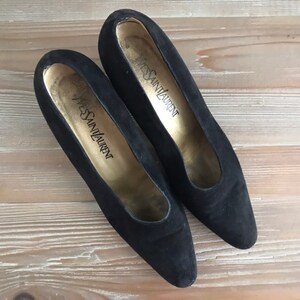 Peut inclure: Une paire de chaussures &agrave; talons en daim noir avec le texte "Yves Saint Laurent" &agrave; l'int&eacute;rieur de chaque chaussure.