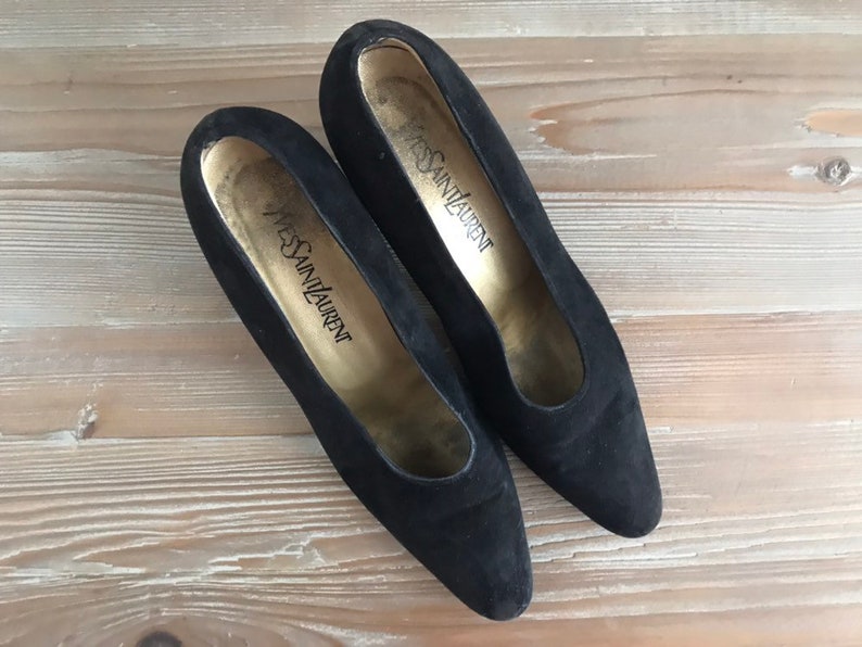 Peut inclure: Une paire de chaussures &agrave; talons en daim noir avec le texte "Yves Saint Laurent" &agrave; l'int&eacute;rieur de chaque chaussure.