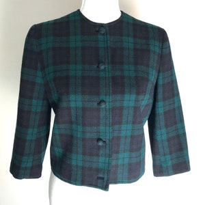 Puede incluir: Una chaqueta de cuadros verde y negro con cierre de botones.