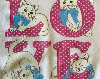 May include: White cotton sweatshirt with a pink and white "LOVE" graphic featuring four white kittens with blue bows. The letters are filled with pink hearts.