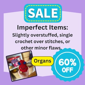 May include: A crocheted red heart with a smiling face, slightly overstuffed, is being held by a hand. The heart is labelled "Organs" and is 60% off. The text "Imperfect Items: Slightly overstuffed, single crochet over stitches, or other minor flaws." is also visible.