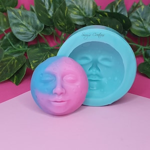 Può includere: Uno stampo in silicone per realizzare un sapone o una candela a forma di luna con un viso. Lo stampo è blu turchese e il prodotto finito è rosa e blu.