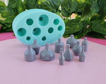 May include: A silicone mold with nine different bottle shapes, next to nine gray bottles made from the mold. The mold is light blue and the bottles are various shapes and sizes.