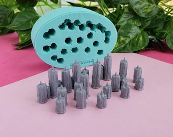 May include: A teal silicone mold with 18 cavities for making candles. The mold is next to a group of 17 gray, textured, pillar candles.