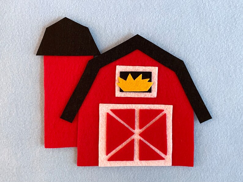 May include: A red felt barn with a black roof and a yellow window. The barn has a white door with a red X.