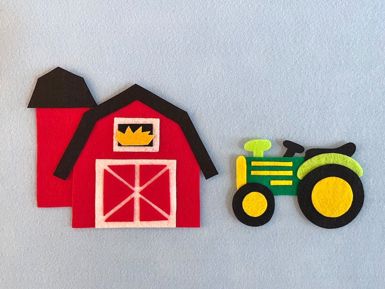 May include: A red felt barn with a black roof and a yellow window. A green felt tractor with black wheels and yellow tires is next to the barn.