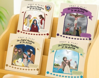 May include: Four children's books titled "Pray & Play" are displayed on a wooden shelf. The book covers feature illustrations depicting religious scenes. Titles include "The Glorious Mysteries," "The Sorrowful Mysteries," "The Joyful Mysteries," and "The Luminous Mysteries of the Rosary."