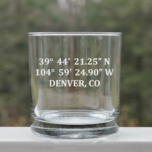 May include: A clear glass tumbler with the coordinates 39° 44' 21.25" N 104° 59' 24.90" W and the text "DENVER, CO" etched on the side.
