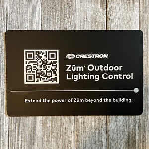 May include: A black rectangular card with a QR code and the text "Zūm Outdoor Lighting Control" in white. The card also includes the text "Extend the power of Zūm beyond the building."