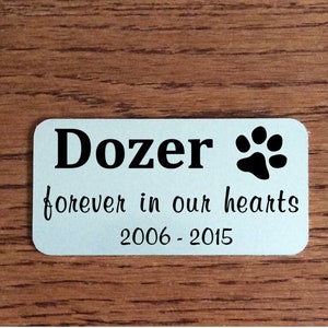 May include: Silver memorial plaque with the name "Dozer" and a black paw print. The text "forever in our hearts" and the dates "2006 - 2015" are also on the plaque.