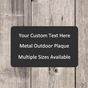 May include: A metal outdoor plaque with a customizable text area, set against a weathered wood background. The plaque is dark gray and the text is white. The text reads "Your Custom Text Here", "Metal Outdoor Plaque", and "Multiple Sizes Available".