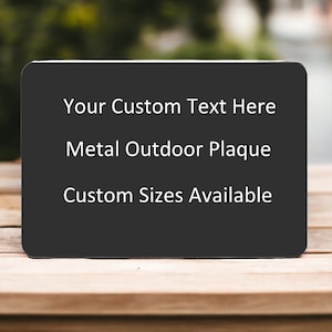 May include: A black metal outdoor plaque with white text that reads "Your Custom Text Here", "Metal Outdoor Plaque", and "Custom Sizes Available".