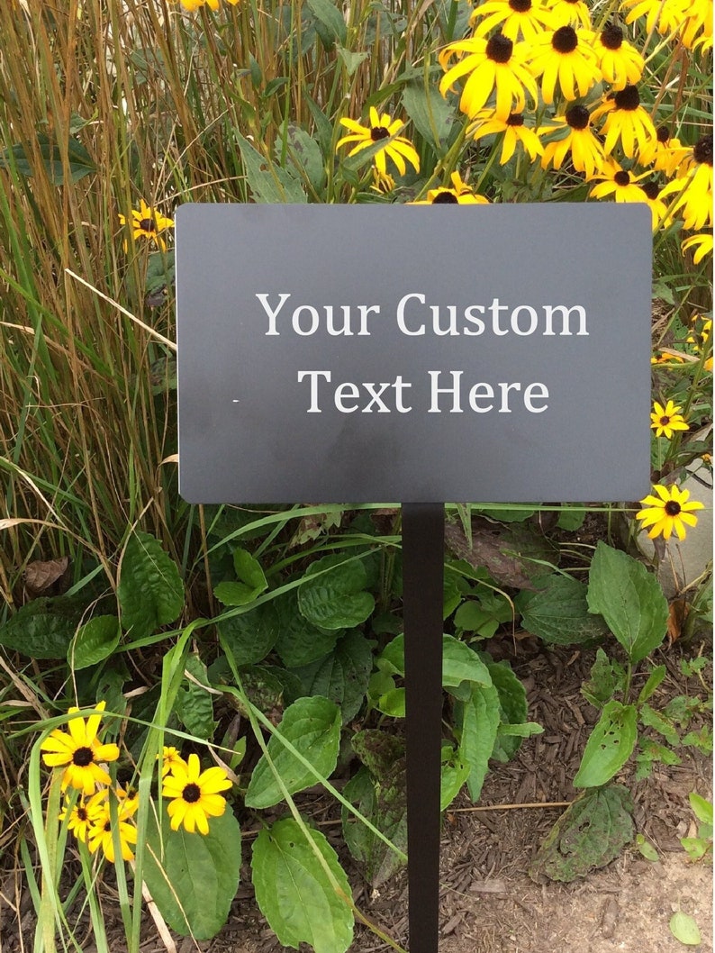 Black metal yard plaque with stake. Engraved with your custom text. Black metal with white text. Custom sizes are available 8x5 inch with 25 inch stake included for easy installation.