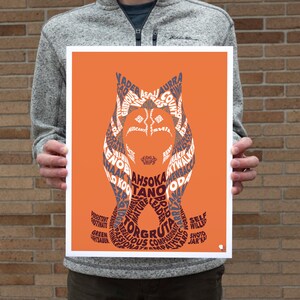 Op de afbeelding: Een oranje achtergrond met een silhouet van Ahsoka Tano's hoofd gemaakt met behulp van tekst. De tekst bevat namen van personages uit het Star Wars-universum, zoals Vader, Grievous en Yoda.