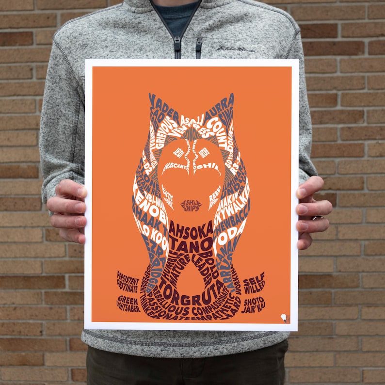 Op de afbeelding: Een oranje achtergrond met een silhouet van Ahsoka Tano's hoofd gemaakt met behulp van tekst. De tekst bevat namen van personages uit het Star Wars-universum, zoals Vader, Grievous en Yoda.
