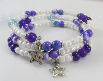 May include: A triple-strand bracelet with white, purple, and blue beads. The bracelet has two silver star charms, one with the words "Just for You".