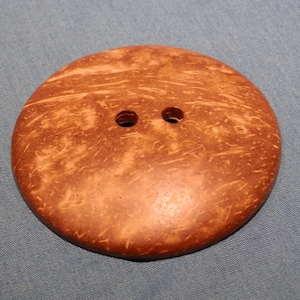 Könnte beinhalten: Ein brauner Kokosnuss-Knopf mit zwei Löchern.