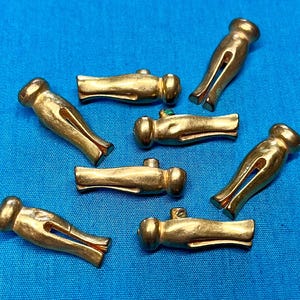 May include: Seven gold-colored metal buttons with a unique design. Each button has a small loop at the top and a split design at the bottom.