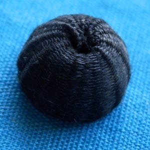 Könnte beinhalten: Ein schwarzer, runder, gewebter Ball mit einer strukturierten Oberfläche.