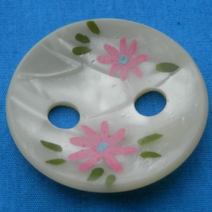 May include: A white, round, two-hole button with a painted design of pink flowers with green leaves.