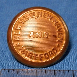 Könnte beinhalten: Ein goldfarbener Metallknopf mit dem umlaufenden Relieftext "NEW YORK NEW HAVEN AND HARTFORD".