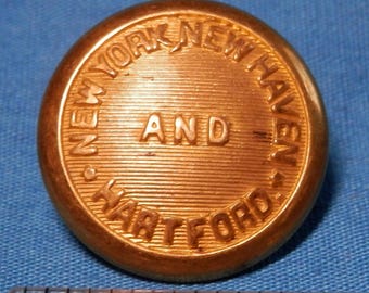 May include: A gold-colored metal button with the text "NEW YORK NEW HAVEN AND HARTFORD" embossed around the edge.