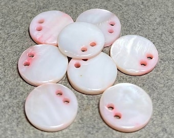 May include: Eight white and pink round shell buttons with two holes each.