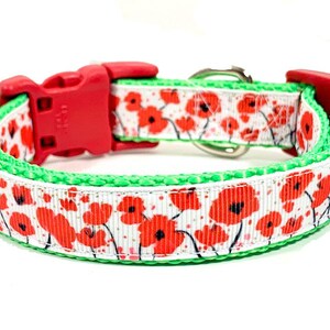 May include: A red and green dog collar with a white background and a red poppy flower pattern.