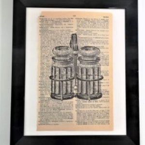 May include: A framed wall art piece featuring a black ink illustration of a double-chambered glass oil and vinegar cruet set printed directly onto a vintage dictionary page with aged, tan-colored paper and visible columns of printed text.