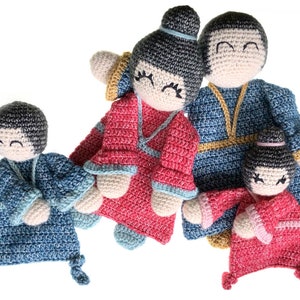 May include: A set of four crocheted dolls, two wearing blue outfits and two wearing red outfits. The dolls have black hair and smiling faces.