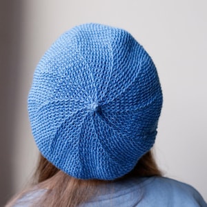 May include: A blue knitted beret hat. The hat is made of a soft, textured yarn and has a classic beret shape.