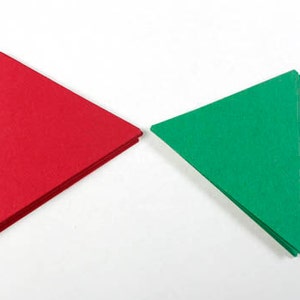 May include: Two folded paper triangles, one red and one green, on a white background.