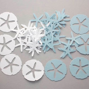 May include: A collection of paper cutouts in the shape of starfish and sand dollars. The sand dollars are white and light blue, while the starfish are white and light blue. The cutouts are scattered on a gray surface.
