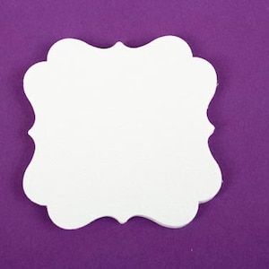 May include: A white, blank, decorative paper tag with a scalloped edge. The tag is on a purple background.