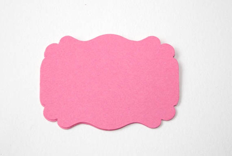 May include: A pink scalloped paper tag with a blank space for writing.