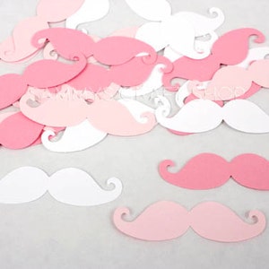 May include: Pink and white paper mustaches. The mustaches are cut out of paper and are scattered on a white background.