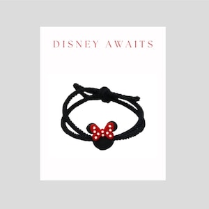 May include: Black string bracelet with a red and white Minnie Mouse head charm. The bracelet has the text "DISNEY AWAITS" on the card.