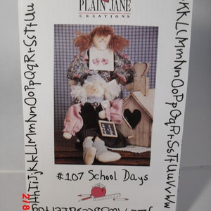 May include: A craft pattern for making a dollhouse with two dolls. The dolls are dressed in school clothes and the dollhouse has a heart-shaped window. The pattern is titled "#107 School Days".
